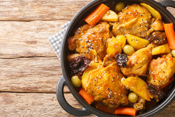 Gallo en chicha stew with chicken, prunes, vegetables, and spices cooked to have a wonderful flavor and aroma closeup on the pan on the wooden table. Horizontal top view from above