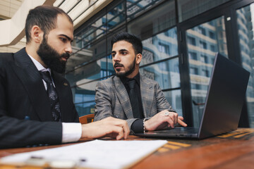 Business people outdoor meeting. A group of business people meet outdoors. Two men are using a laptop. Working break. Team and business support
