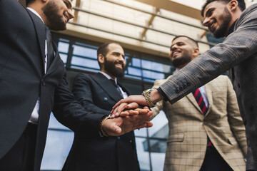 Business people outdoor meeting. Team join forces and celebrate success by throwing their hands up. Stacking hands