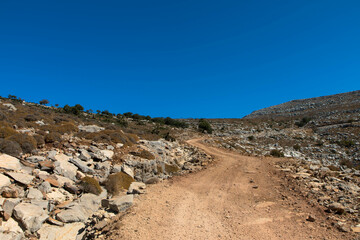 Gravel road to the top of Attavyros mountain. Arid landscape and blue sky. Beautiful hiking area on the island of Rhodes
