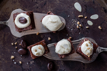 Fünf kleine Stücke Schokoladenkuchen dekoriert mit weißer Schokolade, gehobelte Mandeln und Kaffeebohne werden auf zwei Tortenhebern präsentiert