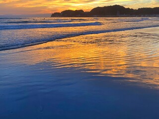 Fototapeta na wymiar 鎌倉の夕焼け、砂浜で見る夕日、海で見る夕陽、砂浜で見る夕焼け、空と海と夕日、オレンジ色に染る空