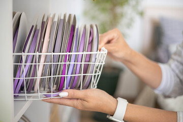 Creative clothes designer female hands putting basket folded decorative ribbons rolls closet storage
