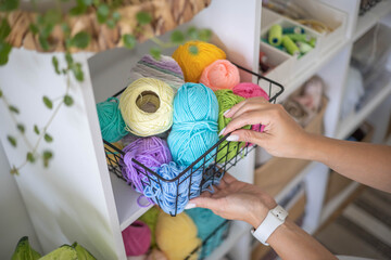 Female hands placing basket with colored ball of yarn art crochet knitting ribbon cotton wool thread