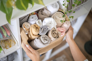 Woman seamstress choosing fabric textile material neatly folded eco basket electric sewing machine