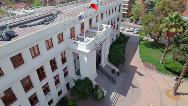 Aerial drone view of Ñuñoa City Hall colonial building with chilean flag fluttering 