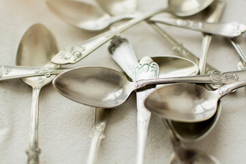 Rustic and silver-plated spoons scattered on the table. Minimal creative concept of teaspoons for tea and dessert.