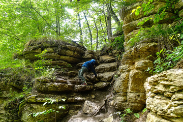 A little boy on the background of rocks in a picturesque forest on the way to the eagle shelf. Mezmai 2021