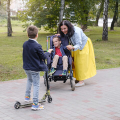 Family with child that has cerebral palsy, wheelchair user walking outdoors. Integration and...