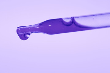 Pipette with liquid essence on a light purple background. Serum for the face. The concept of an...