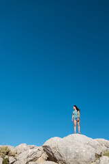 a girl stands on a mountain against a blue sky