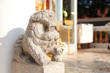 Asian white stone lion statue Chinese vintage style in front of temple on the blur background.