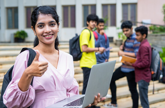 Confidnce Indian Girl Student Showing Thumbs Up By Looking At Camera At College Campus While Using Laptop -concept Of Education Promotion, Successful And Advertaisment.