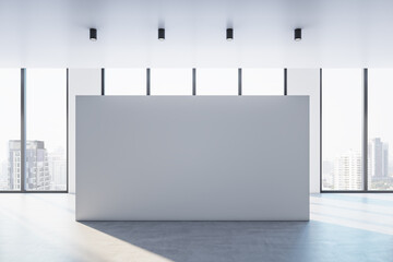 Front view on big blank white billboard with space for advertisement or poster in sunlit empty hall with concrete floor and city view from panoramic windows. 3D rendering, mockup