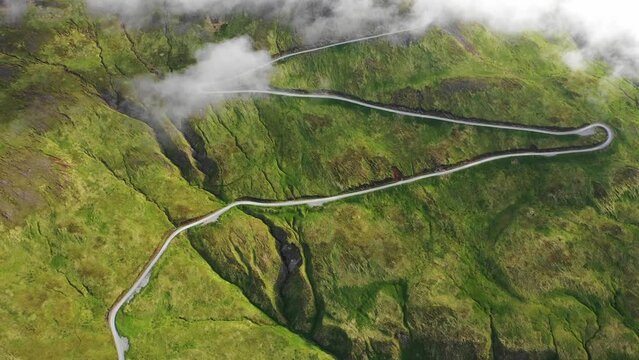Aerial view of a road driving along the mountain crest with low clouds, Unalaska island, Alaska, United States.