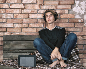 Fototapeta na wymiar Young attractive guy listens to music in headphones at home relaxing on the couch.