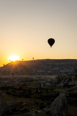 Landscape of the love valley in cappadocia with the silhouette of hot air balloons flying at dawn.