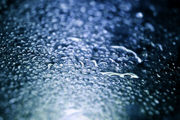 Ultramarine blue water drops on a glass texture. High magnificated macro photograph (Retouched and...