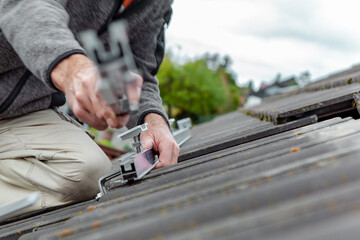 Roofer, worker on the rooftop. Roofing work. Solar Cell Installation. Preparation of Solar panel installation. attaching rails. 
