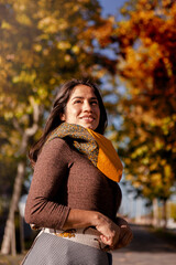Outdoor fashion portrait of young Latin American woman, posing in a park in autumn