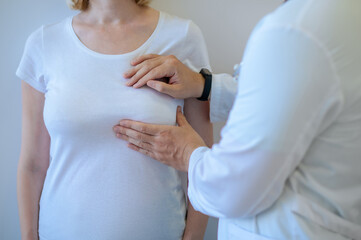 Healthcare worker examining the mammary gland of a female patient