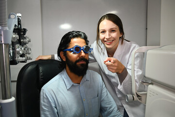 Fototapeta na wymiar Image of happy male patient undergoing vision check with special ophthalmic glasses in ophthalmology clinic