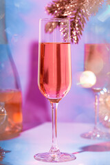 A glass of champagne with a New Year's decoration on a lilac background. Christmas and New Year's vertical card