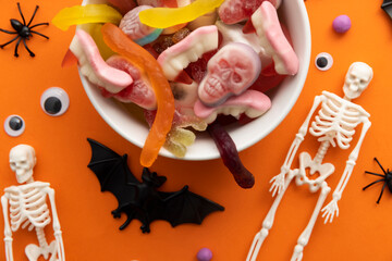 A bowl full of halloween candy sweets on an orange background. Trick or treat background