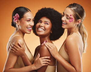 Beauty, flowers and women in makeup, diversity and models on orange studio background. Smile,...