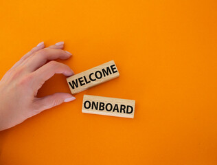 Welcome onboard symbol. Concept words Welcome onboard on wooden blocks. Beautiful orange background. Businessman hand. Business and Welcome onboard concept. Copy space.