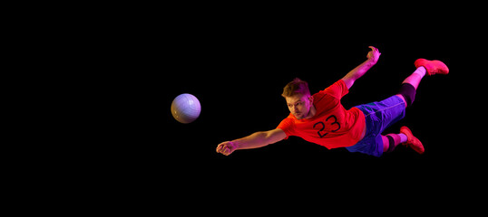 Athlete in motion. Young volleyball player in action isolated on dark background. Fitness, sport,...