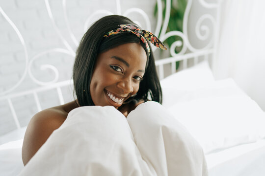 Beautiful young thoughtful african woman sitting in morning bed