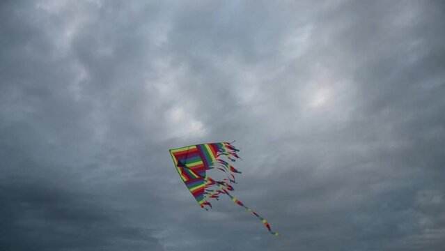 Colorful kite struggling against strong,  stormy wind. Cloudy sky in the background. Darlowko, Poland.