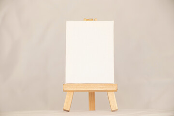 An empty white palette stands on a wooden easel on an isolated background, space for text
