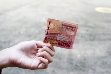 One Hundred Thousand Rupiah Indonesian banknotes are held by women