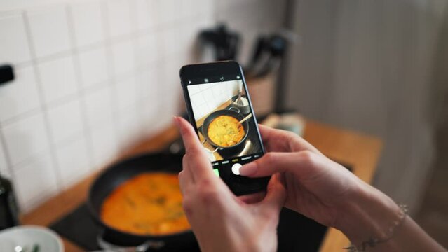 Close up shot of hands taking photo of food with screen phone in kitchen. Smartphone food photography of vegetarian lunch for blogging.