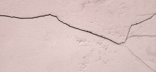 Obraz premium Old pink concrete that cracks buildings or walls leading to obvious crevices.This can cause wear and tear and cause concern or trouble for user. Weathered rough surface. Texture for background, design