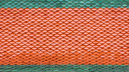 Background and texture of colorful green and orange imbrication ceramic tiles roof of Thai temple