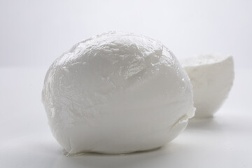 Whole mozzarella with mozzarella cut in half on a white background