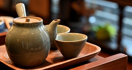 Closeup of a clay teapot and cups on the wooden board