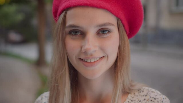 Closeup beautiful young woman with blond hair red beret posing for camera outside. Attractive caucasian young lady in stylish outfit. Females.