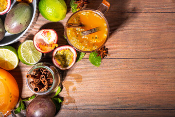 Passion fruit hot tea drink with fruity juice, cinnamon, lime, over wooden background with fresh passion fruit and spices