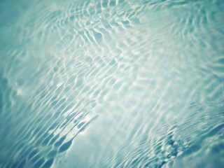 Bluewater waves on the surface ripples blurred. Defocus blurred transparent blue colored clear calm water surface texture with splash and bubbles. Water waves with shining pattern texture background.