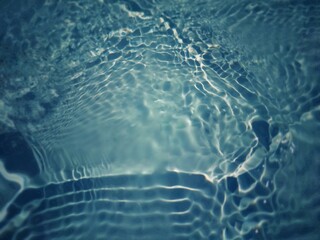 Defocus blurred transparent blue colored clear calm water surface texture with splashes and bubbles. Trendy abstract nature background. Water waves in sunlight with copy space. Blue watercolor shining