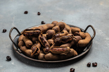 Delicious ripe tamarinds on a basket on a light background, exotic fruit. banner, menu, recipe place for text, top view