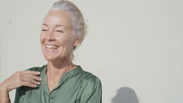 Cinematic footage of a beautiful senior fashion influencer with silver hair and fashionable style. Elderly active woman doing activities outdoor in a modern part of the city