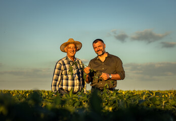 Portrait of two farmers in a soy field at sunset.