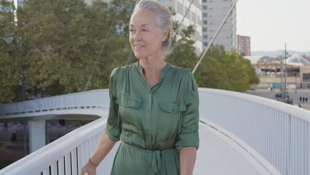 Cinematic footage of a beautiful senior fashion influencer with silver hair and fashionable style. Elderly active woman doing activities outdoor in a modern part of the city