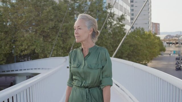 Cinematic footage of a beautiful senior fashion influencer with silver hair and fashionable style. Elderly active woman doing activities outdoor in a modern part of the city