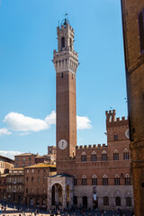 Fototapeta premium Tourists enjoy Piazza del Campo square in Siena, Italy. The historic centre of Siena has been declared by UNESCO a World Heritage Site.